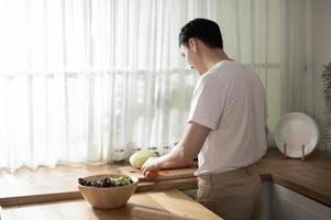 a ásia jovem homem cozinhando , preparando café da manhã com saudável Comida dentro cozinha às casa , saudável estilo de vida foto