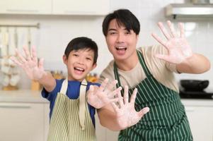 feliz sorridente jovem ásia pai e filho cozinhando dentro cozinha às casa foto