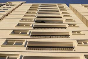 altas casas de vidro azul e branco estão alinhadas em altura. casas são  feitas no mesmo estilo. novo microdistrito, casas com janelas panorâmicas.  contra o fundo de nuvens escuras 13416798 Foto de stock no Vecteezy