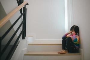 triste criança a partir de isto pai e mãe discutindo, família negativo conceito. pequeno meninas sentado e chorando às a escadaria. foto