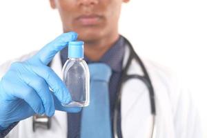 médico segurando um pequeno frasco de desinfetante para as mãos foto