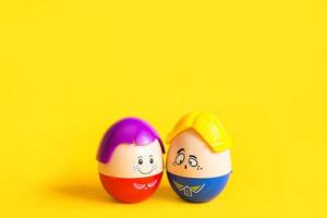dois ovos engraçados menino e menina com rostos em um fundo amarelo - páscoa, primavera. brinquedos infantis-um símbolo de um casal de homens e mulheres, amor, família. espaço de cópia foto