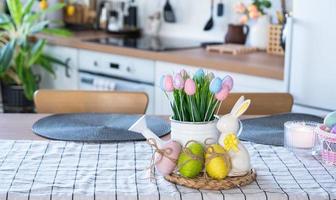 Páscoa decoração do colorida ovos dentro uma cesta e uma Coelho em a cozinha mesa dentro uma rústico estilo. festivo interior do uma país casa foto