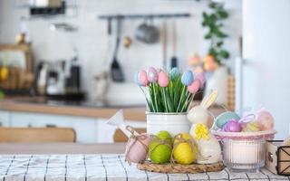 Páscoa decoração do colorida ovos dentro uma cesta e uma Coelho em a cozinha mesa dentro uma rústico estilo. festivo interior do uma país casa foto