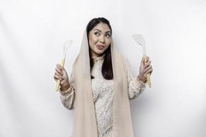 animado ásia muçulmano mulher vestindo uma lenço de cabeça, segurando cozinhando porcelana e sorridente, isolado de branco fundo foto
