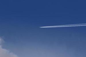 um avião e trilhas de vapor no céu foto