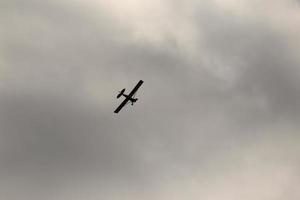 pequeno avião vôo dentro a céu contra Sombrio nuvens foto