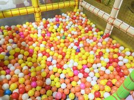 crianças Parque infantil interior às diversão parque com colorida bolas para jogando, dentro a lindo crianças Parque infantil bola colori plástico do jogos quarto foto