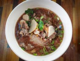 carne Macarrão sopa tigela com carne bola e vegetal em de madeira mesa fundo foto