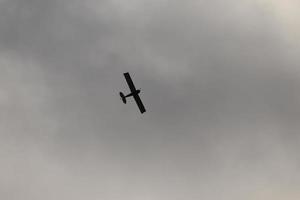 pequeno avião vôo dentro a céu contra Sombrio nuvens foto