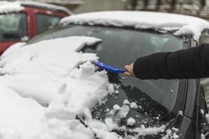 transporte, inverno, clima, pessoas e veículo conceito - mulher limpeza neve a partir de carro com escova foto