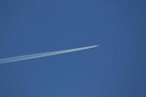 um avião e trilhas de vapor no céu foto