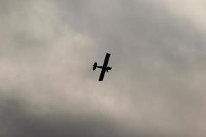 pequeno avião vôo dentro a céu contra Sombrio nuvens foto