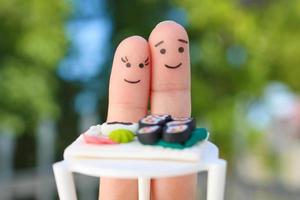 dedos arte do feliz casal. homem e mulher comer Sushi dentro cafeteria. foto