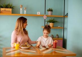 mãe e filha tendo uma café da manhã com fresco espremido sucos dentro a cafeteria foto