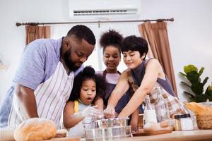feliz africano americano família apreciar juntos enquanto preparar a farinha para fazer biscoitos às casa foto