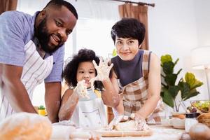 feliz africano americano família apreciar juntos enquanto preparar a farinha para fazer biscoitos às casa foto