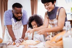 feliz africano americano família apreciar juntos enquanto preparar a farinha para fazer biscoitos às casa foto