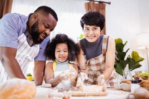 feliz africano americano família apreciar juntos enquanto preparar a farinha para fazer biscoitos às casa foto