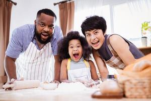 feliz africano americano família apreciar juntos enquanto preparar a farinha para fazer biscoitos às casa foto