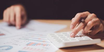 homem de negocios calculando figuras dentro companhia financeiro documentos com uma calculadora, lendo gráfico relatório e o negócio Estatisticas gráficos ,análise e melhoria do corporativo estratégia, estatísticas e dados foto