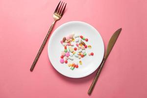comprimidos coloridos em um prato com fundo rosa
