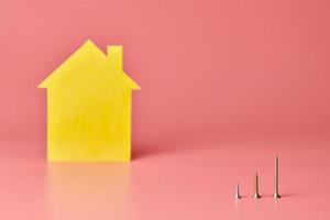 reparo em casa e conceito redecorado. reforma da casa. parafusos e figura em forma de casa amarela no fundo rosa. foto