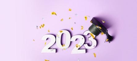 classe do 2023 conceito. de madeira número 2023 com graduado boné em colori fundo com vôo ouropel foto