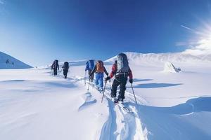 grupo do montanha alpinistas escalar a declive para a pico dentro ensolarado clima com trenós e tendas equipamento para durante a noite permanece foto