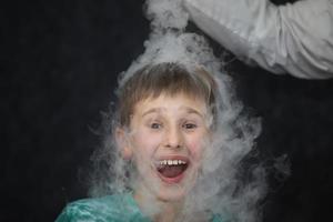 a criança é uma participante dentro científico experimentos. uma Garoto dentro líquido azoto fumaça. foto