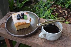 café com um pedaço de bolo na mesa de madeira foto