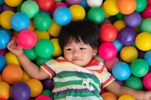 menina asiática feliz um ano e meio jogando bolinhas coloridas na bola de bilhar. o conceito de brincar é o melhor aprendizado para as crianças. foto