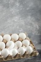 Ovos de galinha crus em uma caixa de ovos em um fundo de mármore foto