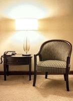 mesa luminária com de madeira cadeira dentro a quarto às noite Tempo foto
