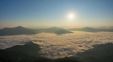 silhuetas através do lindo panorama em a montanhas às nascer do sol. espetacular Visão dentro nebuloso vale coberto floresta debaixo manhã céu. foto
