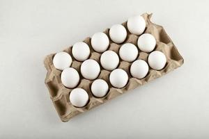 ovos de galinha crus em uma caixa de ovos em um fundo branco