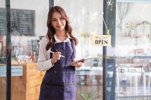 retrato do uma mulher, uma café fazer compras o negócio proprietário sorridente belas e abertura uma café fazer compras este é dela próprio negócios, pequeno o negócio conceito. foto