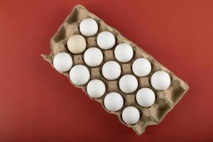 recipiente de ovos brancos em um fundo vermelho foto