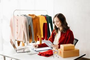 moda blogueiro conceito, jovem ásia mulheres vendendo roupas em vídeo streaming.startup pequeno o negócio sme, usando Smartphone ou tábua levando receber e verificação