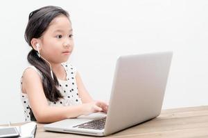 fofa aluna menina com computador portátil computador em a mesa foto