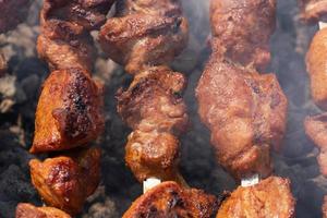 fechar-se Visão grelhado saboroso carne de porco shish Kebab cozinhando em espetos carvão grade foto