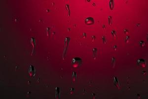 água gotas em vidro em uma vermelho fundo. foto