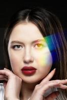 lindo menina modelo com sensual lábios em uma Preto fundo com a ótico arco Iris efeito.