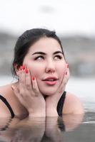 retrato do mulher abraçando face com dela Palmeiras, de brincadeira olhando acima dentro água do ao ar livre piscina foto