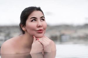 autêntico mais Tamanho morena modelo tomando banho e relaxamento dentro mineral água do ao ar livre piscina às spa foto