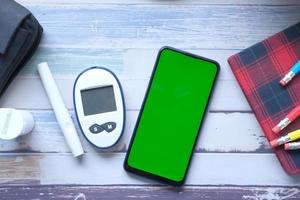 Smartphone e ferramentas de medição de diabetes em fundo de madeira foto