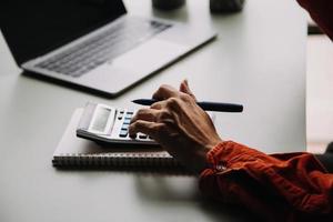 trabalho em equipe do ásia o negócio pessoas discutindo e calculando com calculadora em avaliação dados dentro conferência sala. com a crescimento e apontando para a gráfico gráfico financeiro conta. foto