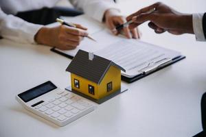 modelo de casa com agente imobiliário e cliente discutindo contrato para comprar casa, seguro ou empréstimo de fundo imobiliário.