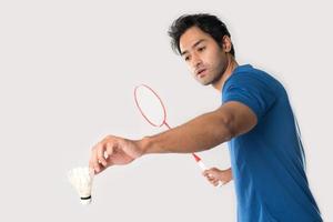 um jogador de badminton em roupas esportivas fica segurando uma raquete e peteca. foto