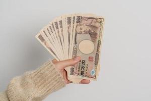 mão de uma mulher segurando a pilha de notas de iene japonês. dinheiro de mil ienes. dinheiro do japão, impostos, economia de recessão, inflação, investimento, finanças e conceitos de pagamento de compras foto